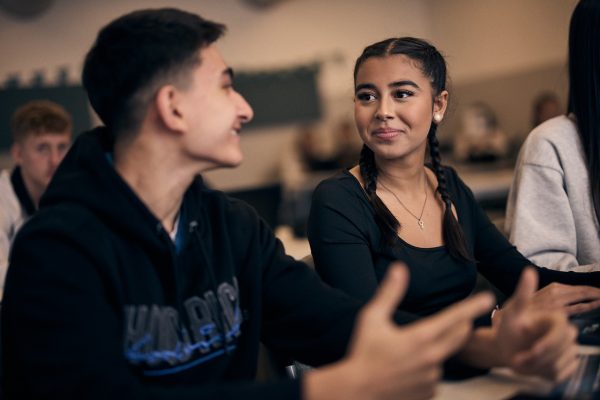 Två elever sitter i ett klassrum och diskuterar