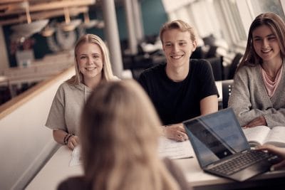 Elever sitter i skolans gemensamma lokaler och skrattar.