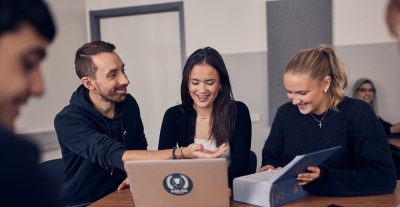 Lärare hjälper två elever med en uppgift i en skolbänk