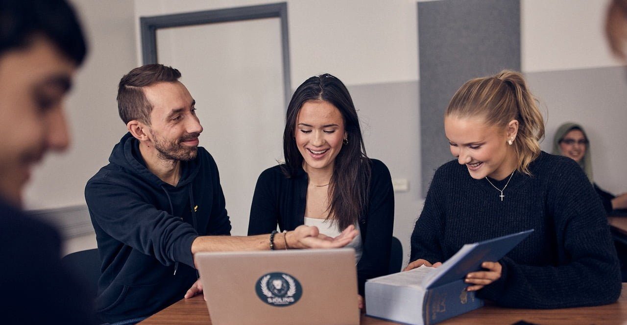 Lärare hjälper två elever med en uppgift i en skolbänk