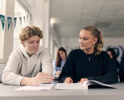Två elever i ett klassrum som läser en bok