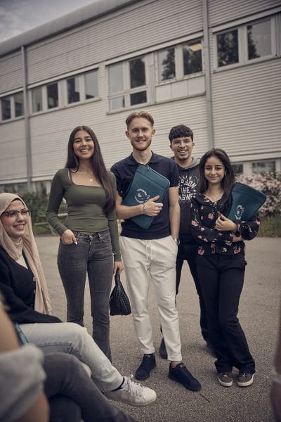 Glada elever står utomhus och tittar in i kameran.