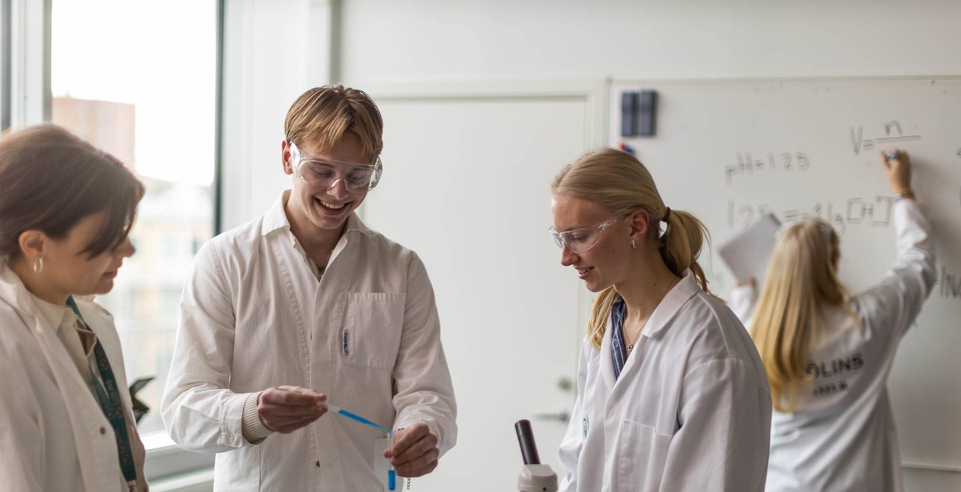 Elever i vita rockar och skyddsglasögon laborerar