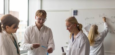 Elever i vita rockar och skyddsglasögon laborerar