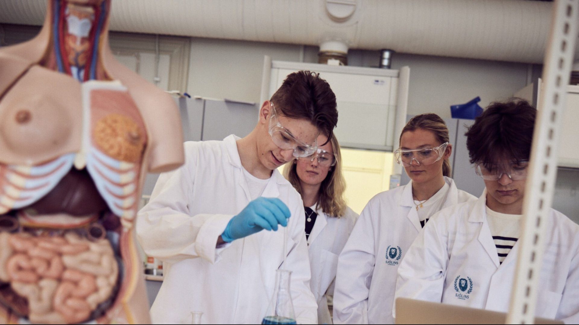 Elever i vita rockar och skyddsglasögon experimenterar