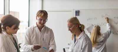 Elever i vita rockar och skyddsglasögon experimenterar
