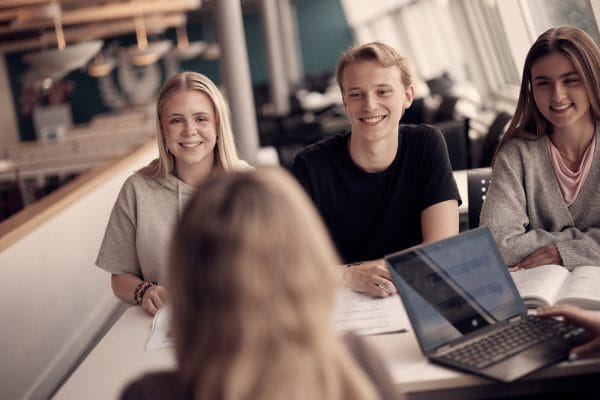 Elever sitter i skolans gemensamma lokaler och skrattar.