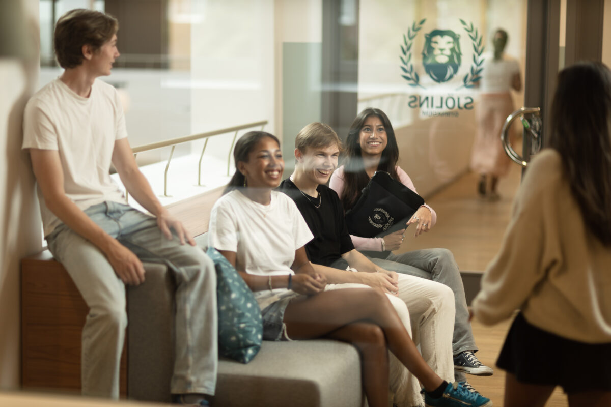 Elever sitter i en soffa i en skolkorridor
