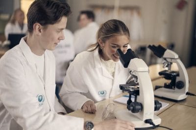 Elev i labbrock utför ett kemiexperiment med en rosa vätska.
