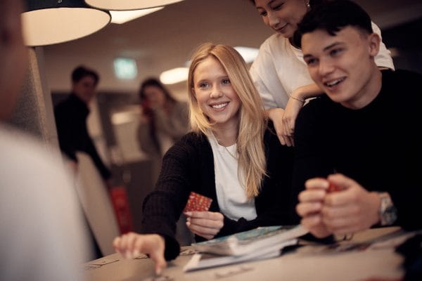 Glada elever som spelar kort tillsammans i skolans lokaler.